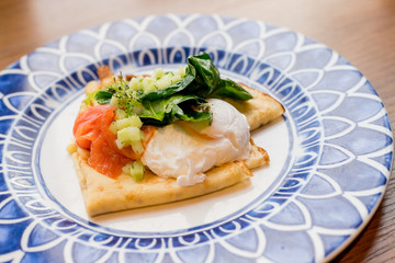 Savory crepes with salmon and poached egg.Tasty breakfast with pancakes, smoked salmon, pouched egg with spinach,Lettuce, onion, Hollandaise sauce.Fresh, healthy breakfast .