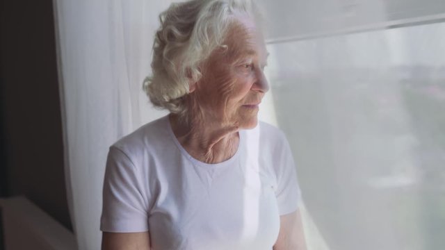 Senior woman sitting on windowsill.