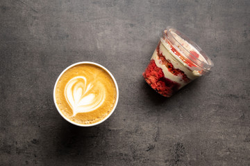 Dessert in plastic container and cup of cappuccino top view on grey background