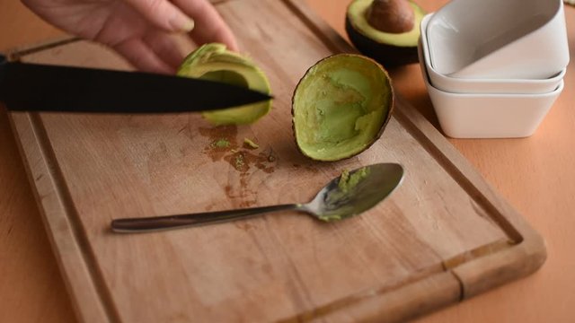 Verarbeiten einer Avocado. Frauenhand schneidet eine Avocado in Stücke.
