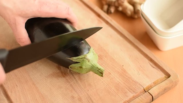 Aubergine zubereiten. Frauenhand schneidet aubergine in Scheiben