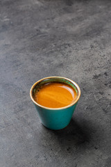Espresso in beautiful greenish-blue cup on gray background