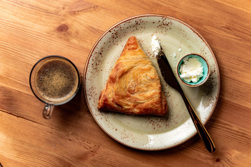 samsa with cream cheese on a plate and coffee on wooden table top view