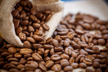 Black roasted coffee beans in a bag.  Coffee beans spilled out of a small bag.