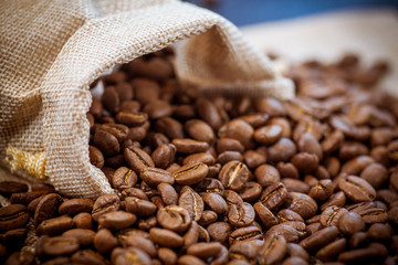 Cafe beans get enough sleep from their bag on a sackcloth background. Black coffee beans close-up....