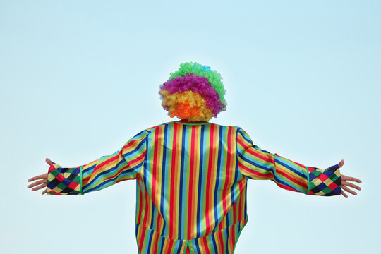 Clown Standing With His Back To Us, Isolated Against A Light Blue Background