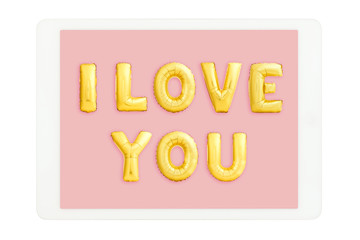 White tablet computer with golden I LOVE YOU words made of inflatable balloons isolated on white background