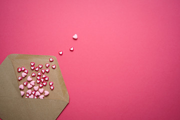 Valentines day copy space. Pink and red Heart shape beads on pink background with brown envelope. 