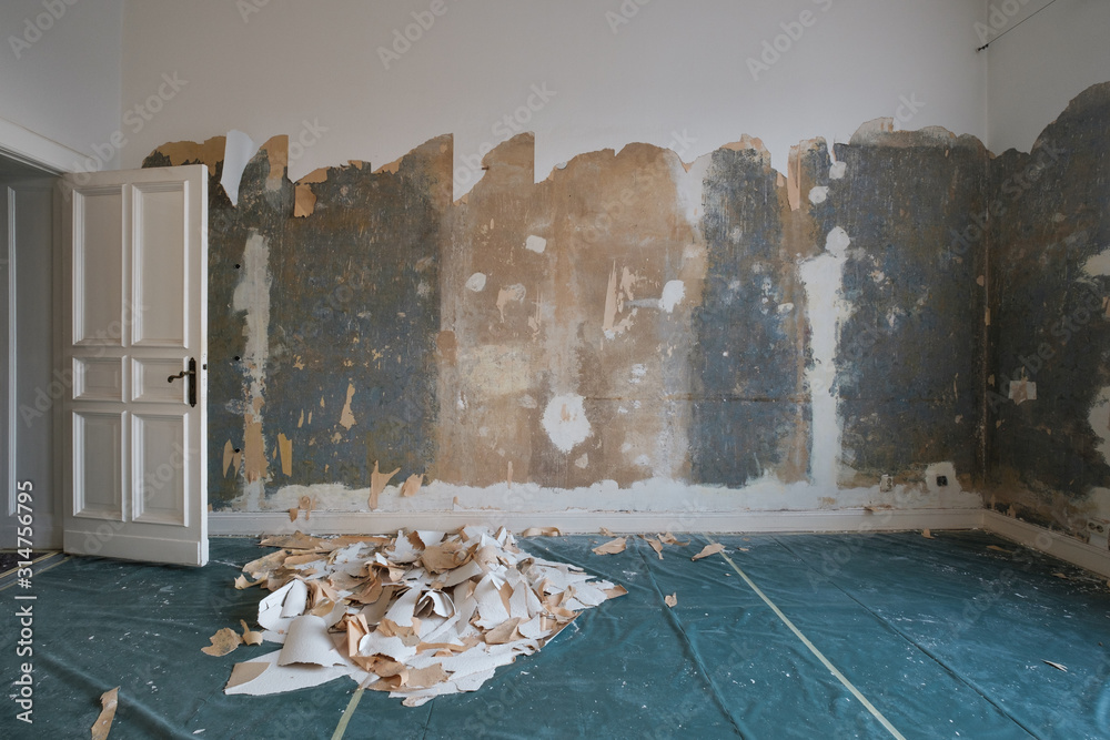 Wall mural removing wallpaper from wall in room during flat renovation