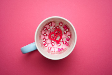 Valentines day copy space. Pink and red Heart shape beads on pink background with mugs. 