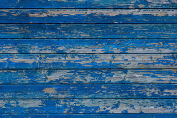 Facade wall of an old wooden rural house. The blue paint on the boards partially flew around. Background. Texture.