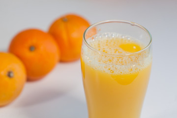 Glass of orange juice on a table with oranges on the background.