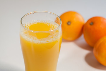 Freshly squeezed orange juice with fruits on a white kitchen table. Glass of fresh orange juice isolated on white background.