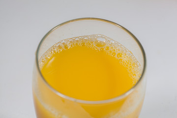 Glass with orange juice on a white table.