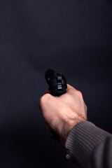 Male hand with gun isolated on black background. Man with a gun ready to shoot, focus on the weapon.