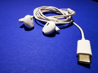 White headphones for a smartphone or an MP3 player with loud and quiet switch on blue background