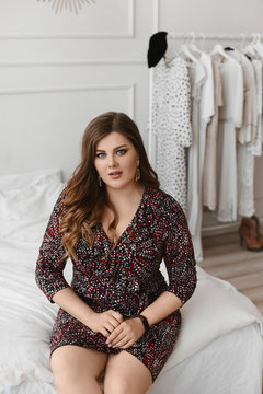 Shocked plus size model girl sitting on a bed and looking in