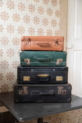 Four antique suitcases stacked on a table