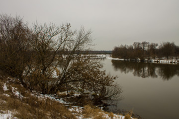 Winter landscape with river and reflections and snow on the Bank on a cloudy day