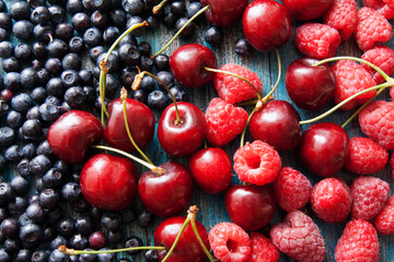 Raspberries, cherries, blueberries on the painted surface