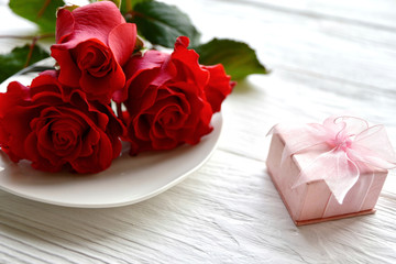 Tree red roses and gift box on a white wooden background. St. Valentine's Day background.