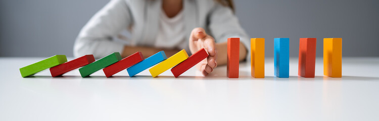Businessperson Hand Stopping Colorful Blocks From Falling - obrazy, fototapety, plakaty