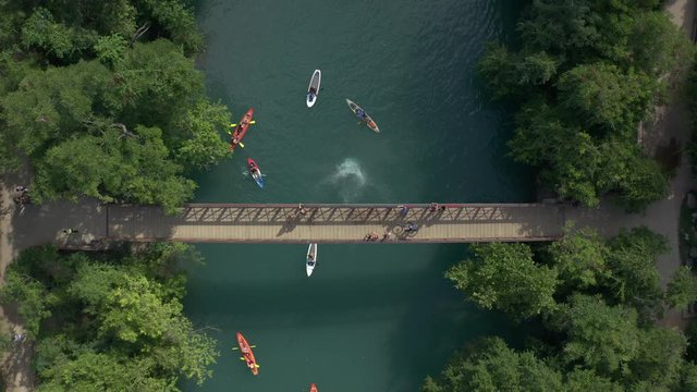 Person diving off bridge into creek with kayaks and paddle boards in Austin Texas