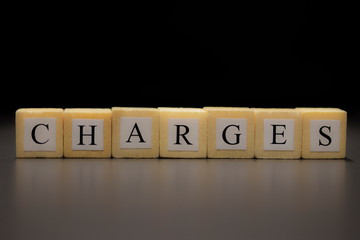 The words CHARGES written on wooden cubes isolated on a black background...