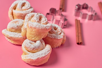 Heap of many homemade baked buns in form of rose spangled of powdered sugar near metal stencils and...