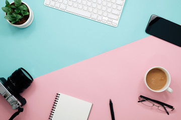 Office desk table with notebook, keyboard, pen, cup of coffee and flower. Top view with copy space.