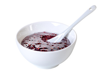 White ceramic bowl of blackberry jam isolated on white background
