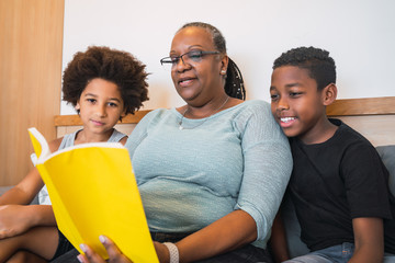 Grandmother reading a book to grandchildren.