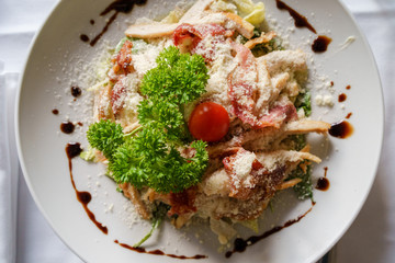 High angle top view on Caesar salad served in a white plate on the table fresh with some parsley