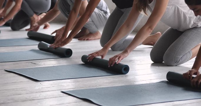 Multiethnic people folding mats finished yoga session at sport studio