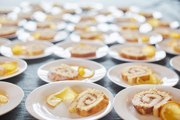sponge rolls with jam and a slice of orange on white plates. background