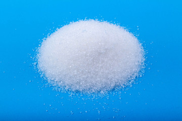 Obraz na płótnie Canvas white granulated sugar on an blue background