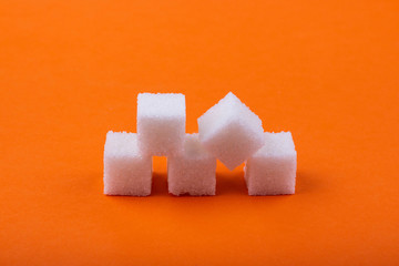Cubes of white sugar on an orange background