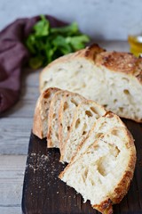 Homemade Freshly Baked Country Bread  made from wheat and whole grain flour on a gray-blue background. French Freshly baked bread. Slicing homemade bread into slices on a wooden board