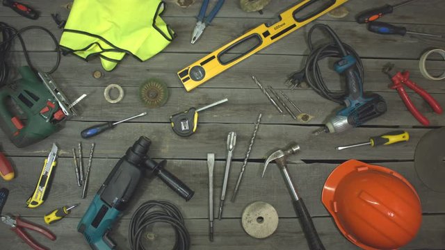 A variety of electro and hand tools and special clothing. Top view.  On the table are tools for various types of construction and repair work on wood, metal, concrete, plastic and other materials.