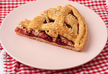 triangular slice of baked cherry pie on a pink round plate