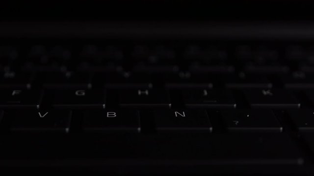 illuminated keyboard buttons letters in RGB colors on modern black laptop