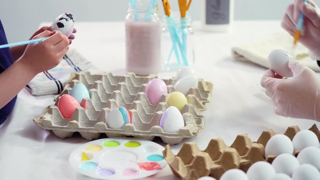 Little girl painting craft Easter eggs with acrylic paint.