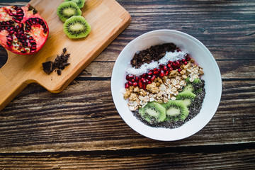 Smoothie bowl for breakfast and wooden table with ingredients. Top view.