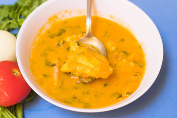 Braised Fish Fillet or Stew fish. Cooked fish made with tomatoes, onions, peppers and coriander. Blu Background.