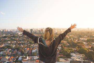 Girl with wide arms open at the top of a building in Sao Paulo, Brazil