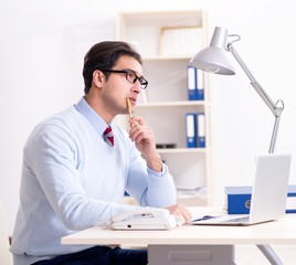 Young handsome businessman employee working in office at desk