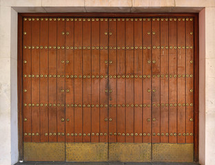 old wide wooden door with golden metal rivets - closed gate