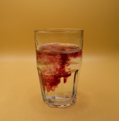 Glass of water with burst of color from water enhancer