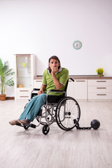 Young male invalid in wheel-chair suffering at home