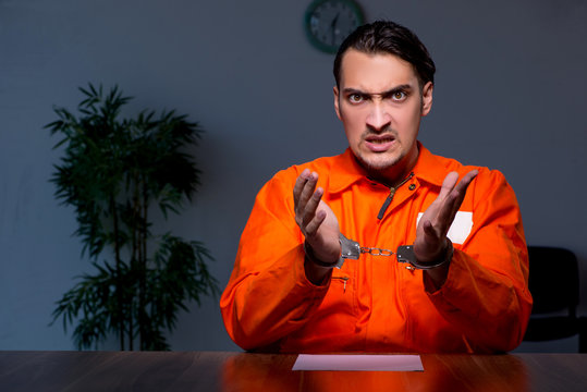 Young convict man sitting in dark room